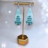 Festive Snowy Christmas Tree Earrings shown with intricate snow details, handmade from polymer clay, and set on hypoallergenic stainless steel.